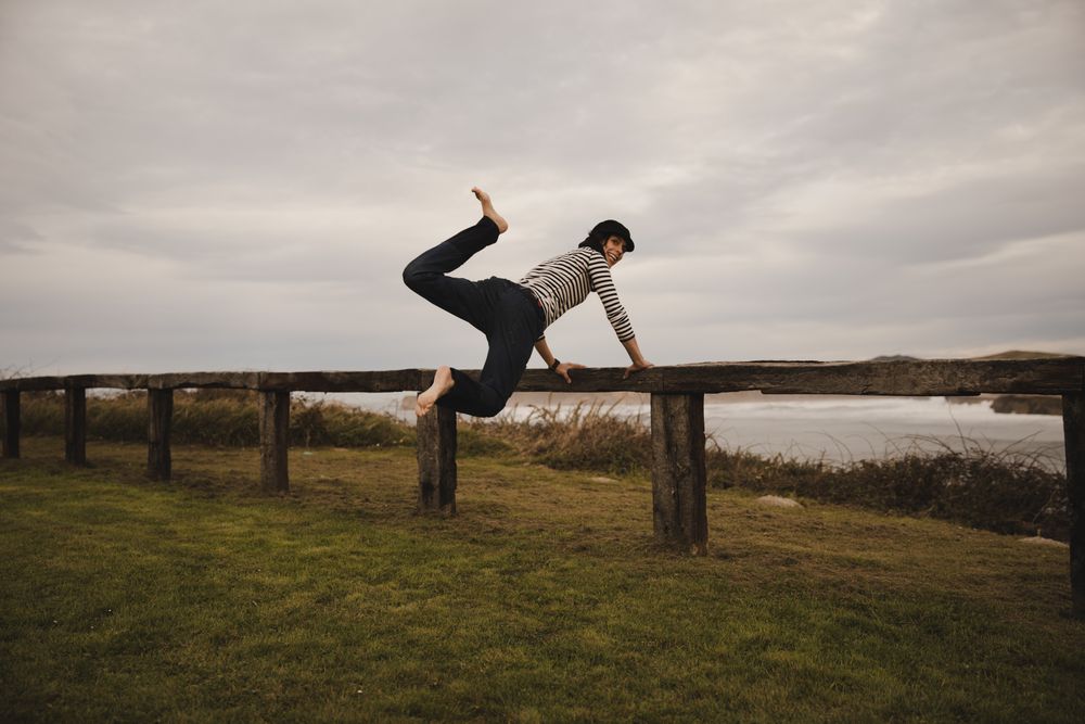 Woman jumping near bench on shore near water