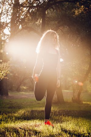 Sportive woman standing on meadow in sunlight