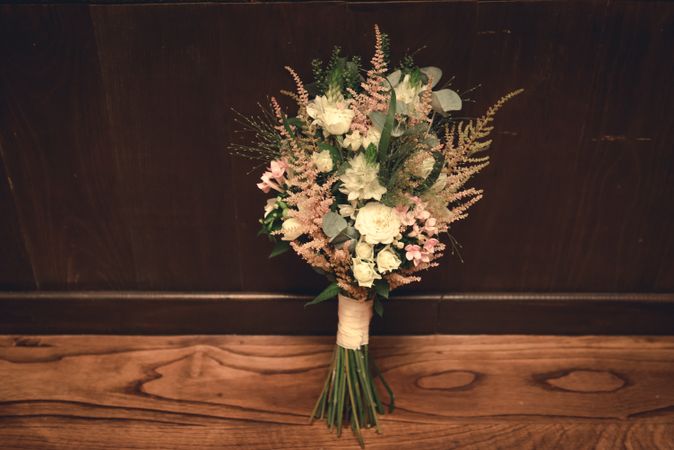 Bouquet of fresh flowers on floor near wall