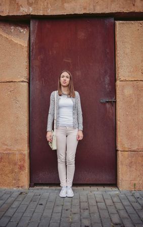 Young woman standing in front of large old door on European street