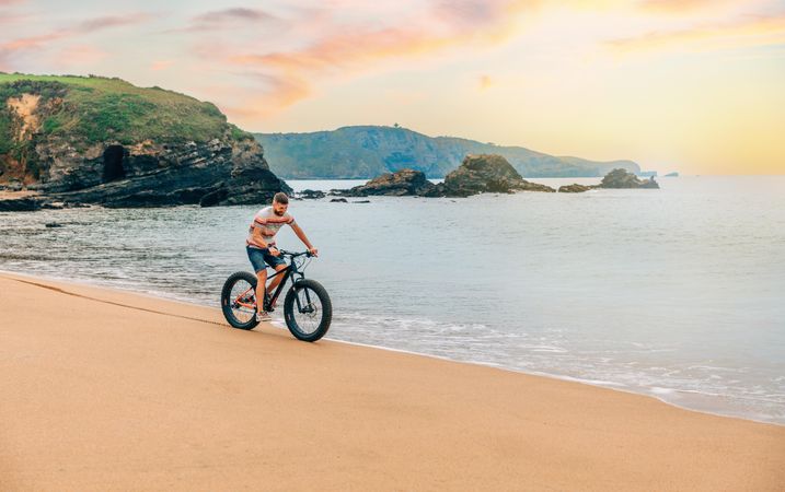 White male riding bicycle on beautiful shoreline