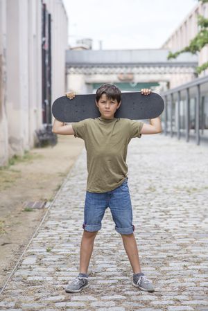 A teenage boy carrying skateboard and smiling