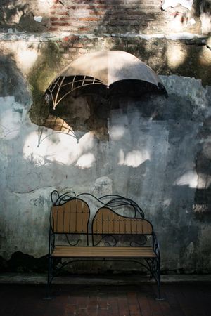 Antique brench on brick wall with  umbrella hanging on wall. Vintage brench park.