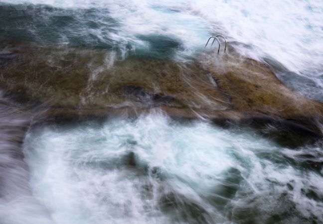 Stone shore with ladder between water
