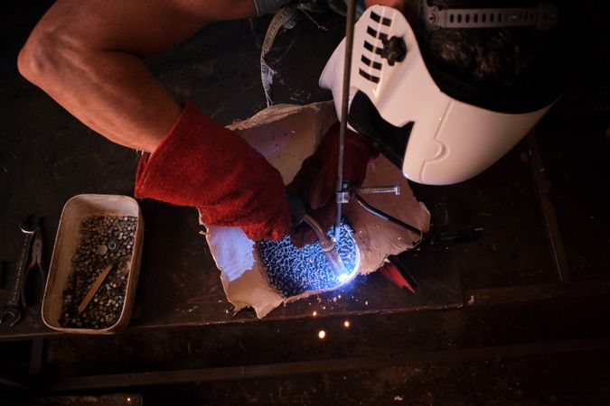 Crop male artisan in process of welding in garage