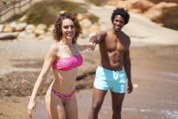 Happy diverse couple holding hands on beach