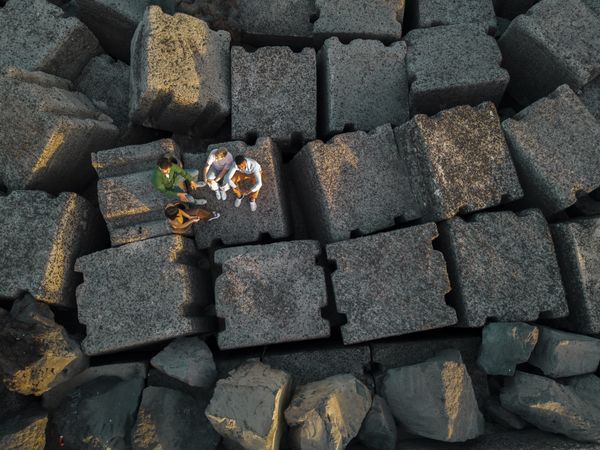 Diverse Friends Gathered on Tetrapod Seashore Blocks - Aerial View