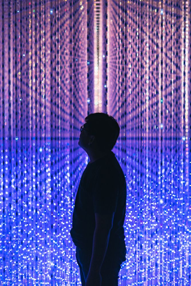 Man standing beside blue purple lit wall