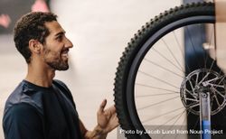 Man aligning a bicycle wheel in a repair shop 56oRe4