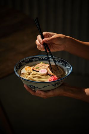Crop person having traditional ramen soup