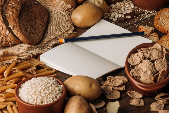 Wholegrain food empty notebook and freshly baked rye bread on table