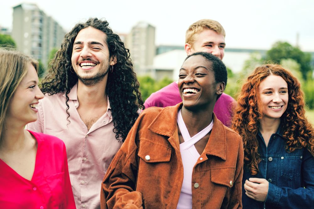 Diverse friends laughing and joking together in a park