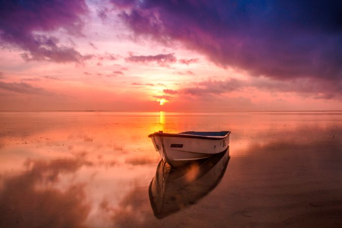 Boat on sea shore during sunset