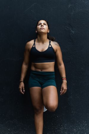 Hispanic sportswoman standing near wall