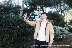Man with smile is taking a selfie in front of trees beXXAp
