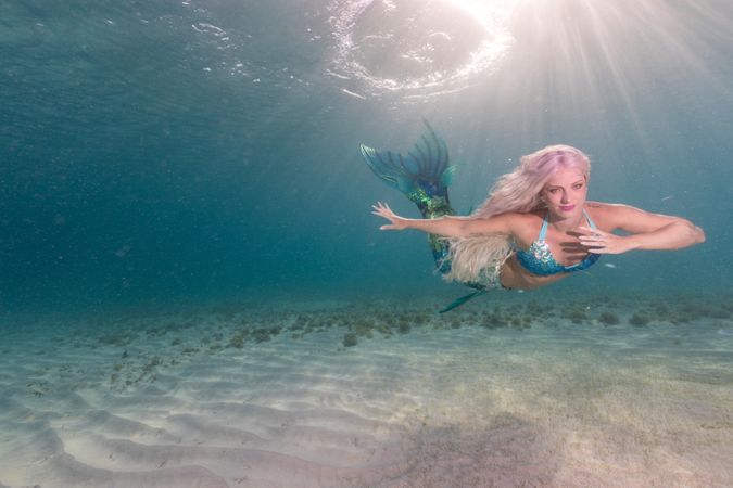 Blond fairytale female mermaid swimming underwater