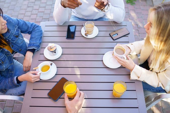 Looking down at group of friends with coffee and juice at outdoor table