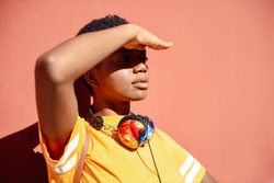 Female with headphones around neck looking into the sun
