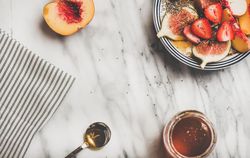 Flat-lay of yogurt bowl with fruit, honey, spoon, copy space