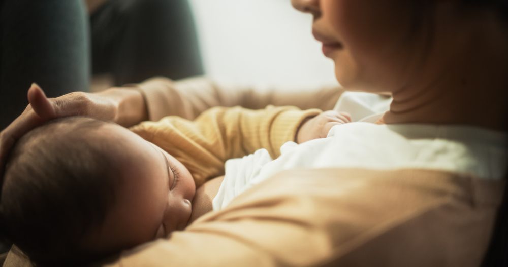 Portrait of Cute Baby Falling Asleep While Being Breastfed by his Mother.
