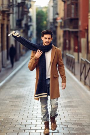 Man adjusting his scarf while walking down the street