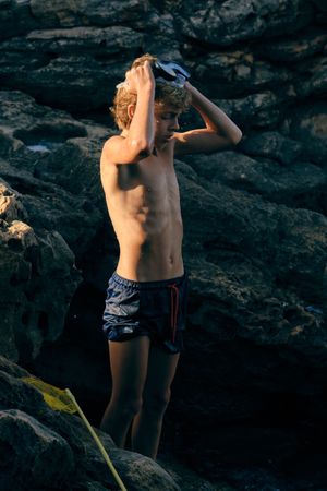 Boy putting on diving mask on mountain