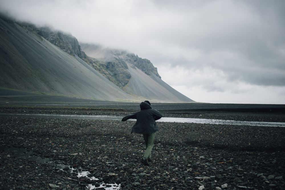 Man walking on rocky beach on overcast day