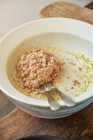 Ceramic bowl with minced raw meat and sauce on wooden table