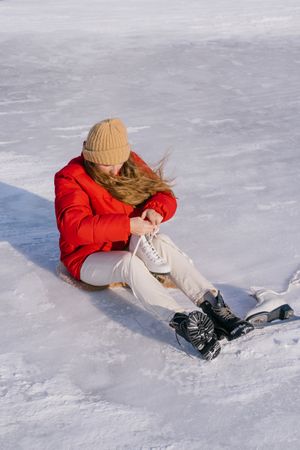 Woman sitting on snow and changing boots