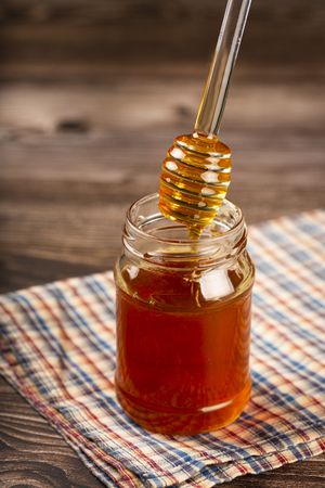Honey in glass jar on the table.
