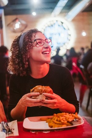 Young woman eating burger in cafe