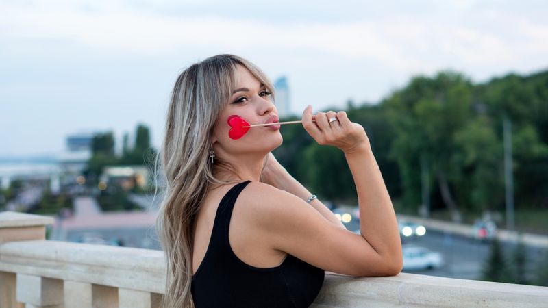 Beautiful young woman with red heart shaped lollipop