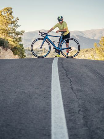 man resting while riding a bicycle on a mountain road