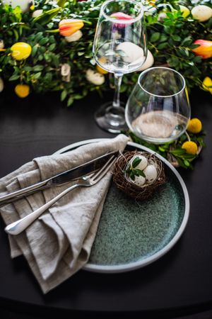 Easter table setting with nest on plate and leafy tulip centerpiece