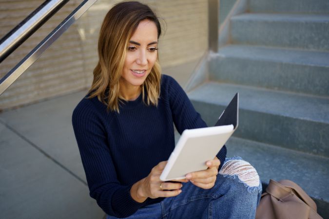 Woman relaxing reading e book on steps