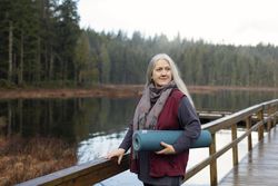 Woman holding a yoga mat on a dock