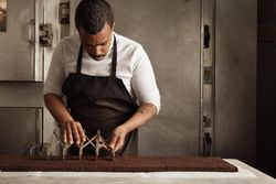 Man in apron slicing cake in professional kitchen