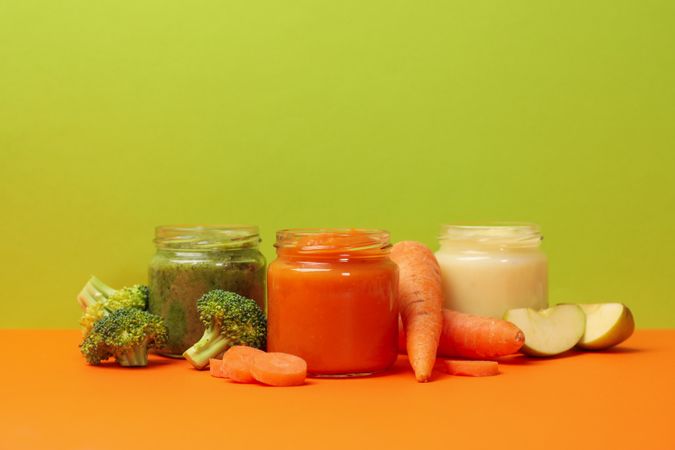 Composition with vegetable puree on orange table. Baby food