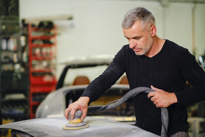 Mechanic grinding paint from car detail