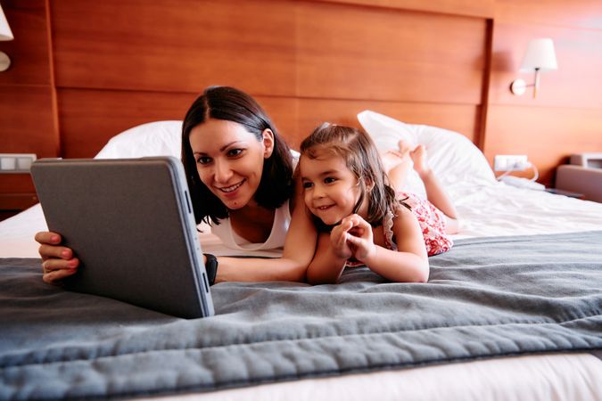 Little girl and her mother using a tablet in a hotel room