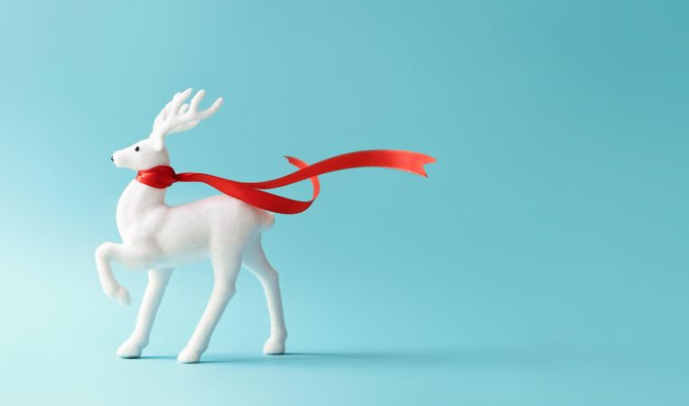 Reindeer with red scarf on pastel blue background