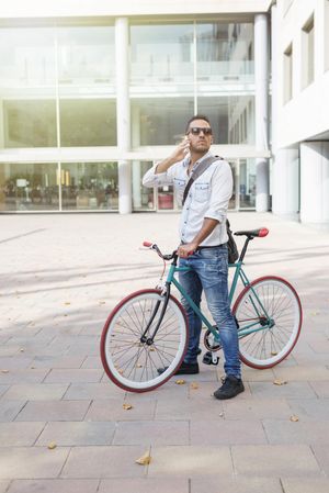 Male sitting on colorful bike with phone to his ear
