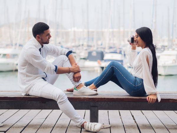 Woman taking photo and sitting with man on bench