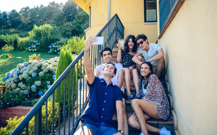 Young happy people taking a selfie with smartphone on stairs outside
