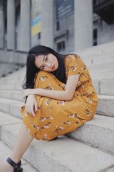 Girl in orange dress sitting on concrete stairs