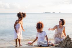 Family playing and building sand castle at tropical beach in summer