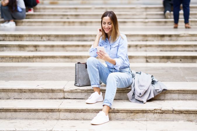 Woman sitting on outdoor steps checking phone