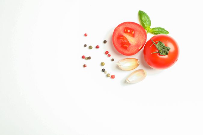 Fresh cherry tomatoes with basil, spices and garlic on plain background, space for text and top view. Ripe vegetables