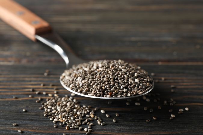 Spoon with chia on wooden background, copy space