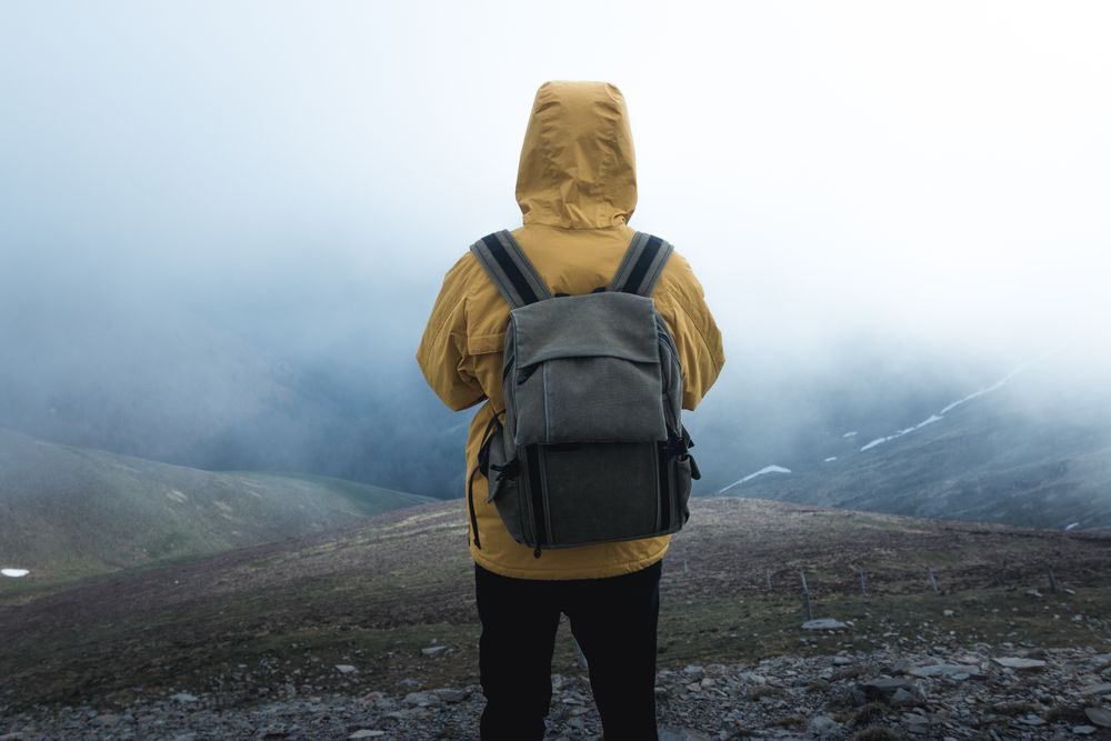 Anonymous traveler on hill on misty day